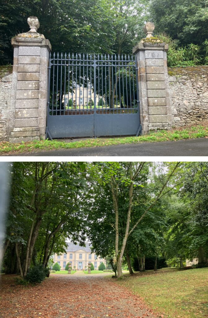 A pair of ornate iron gates framed by stone pillars, leading to a grand house partially obscured by trees.